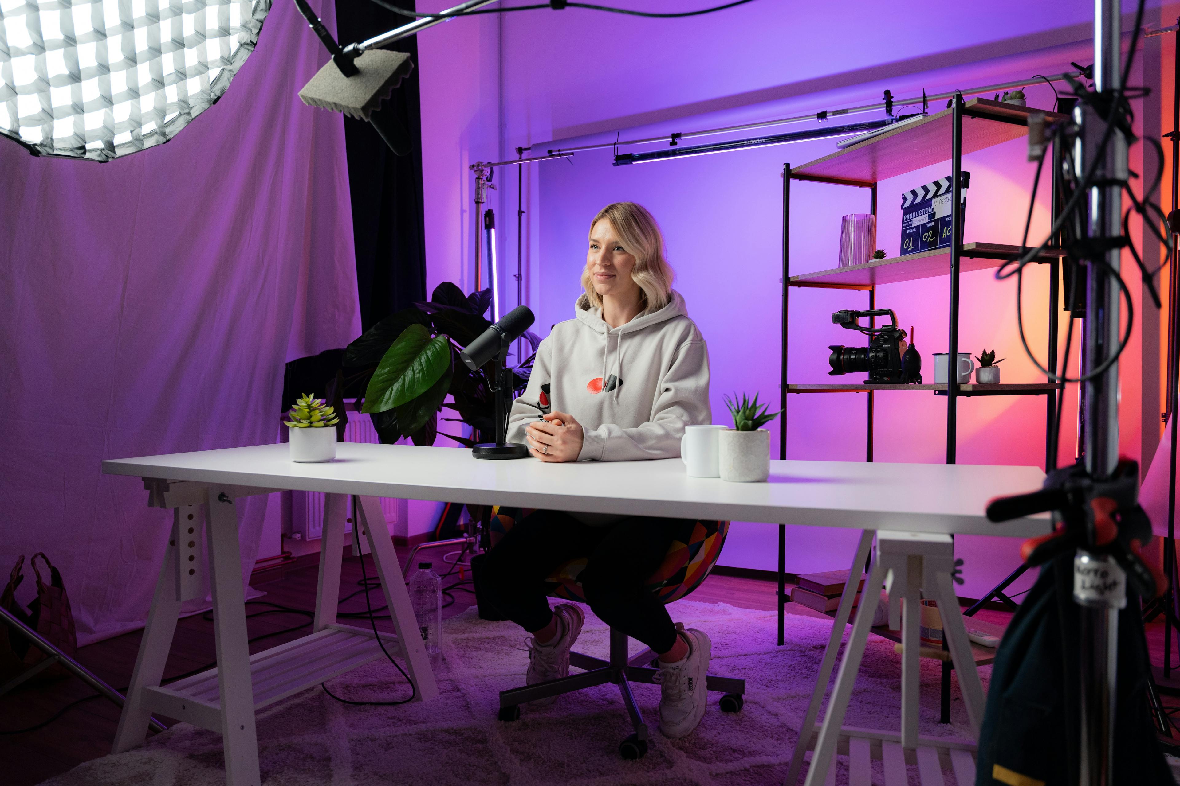 Creator Sitting At Desk with Film and Audio Equipment In a Purple Lighted Background